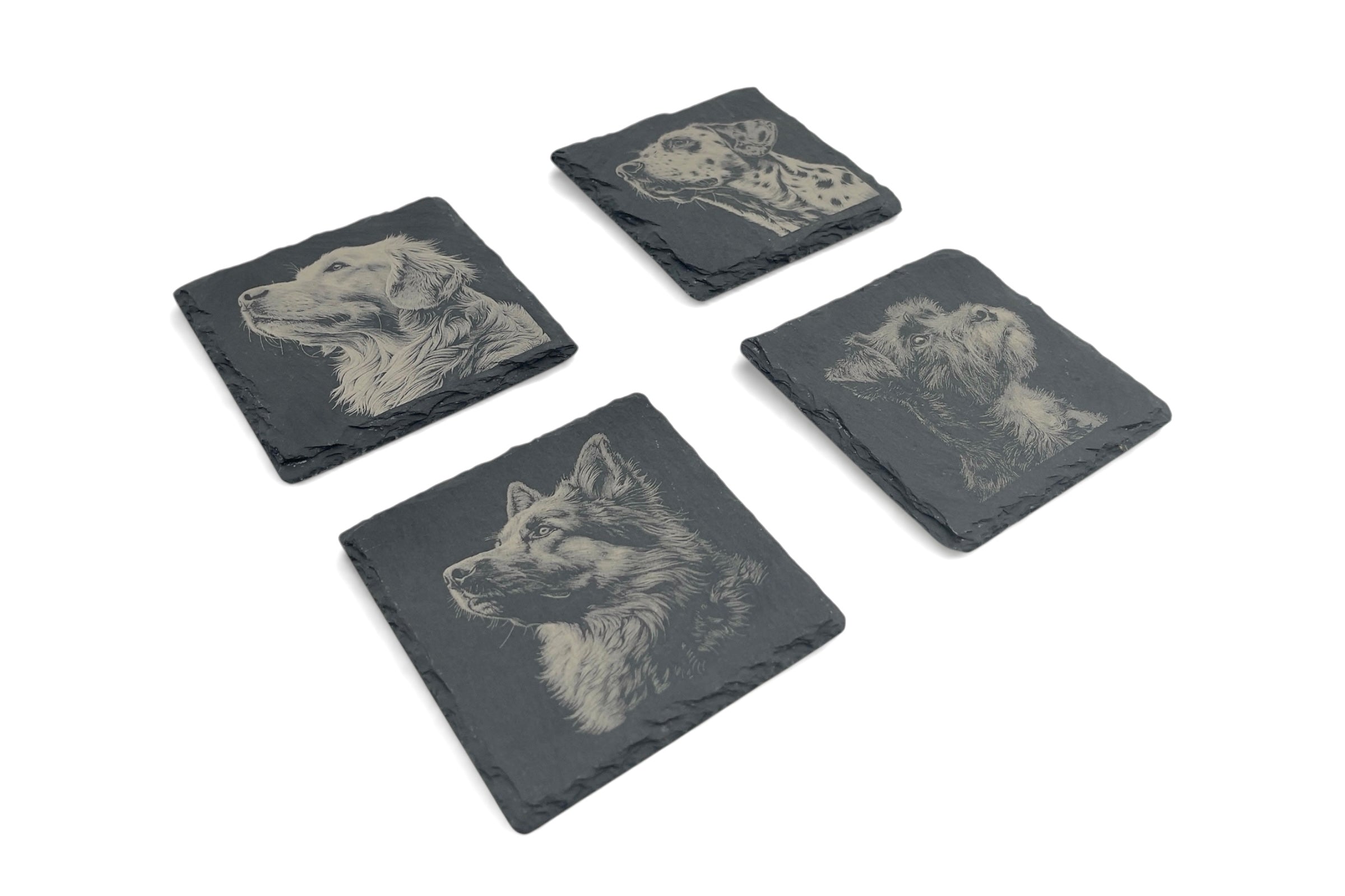 Four slate coasters with laser etched dog designs, on a white background.