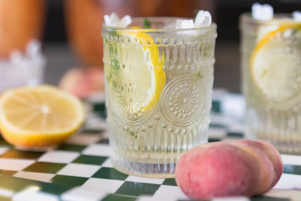 FINCHCRAFT Amore glass tumbler with etched floral pattern containing a refreshing drink with lemon slices