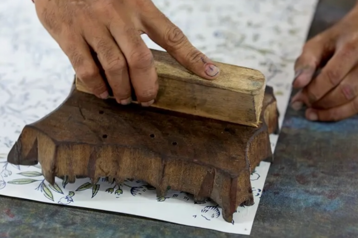 FINCHCRAFT artisan hand-block printing a songbird and floral motif onto blush cotton wrapping paper