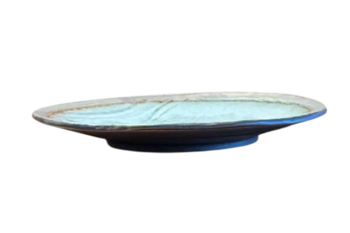 FINCHCRAFT grey glazed stoneware plate with a shallow, irregular form and a natural bisque edge, side view.