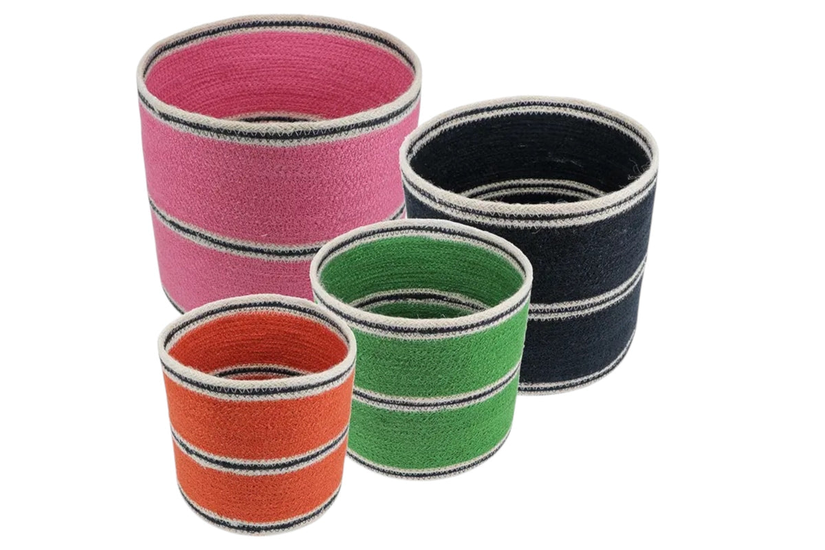 FINCHCRAFT set of four round woven jute storage baskets in pink, navy, green, and orange with striped detailing.