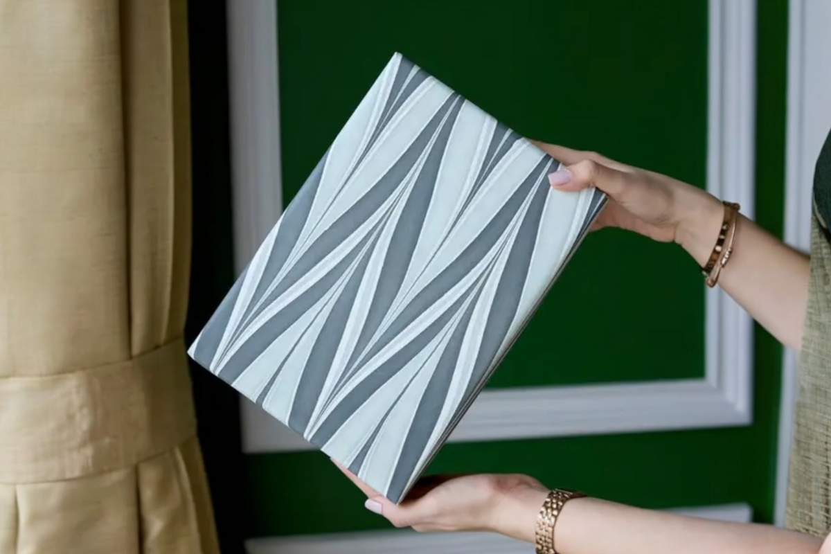 FINCHCRAFT hand marbled cotton wrapping paper with grey and white wave patterns held by a person in a green room.