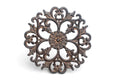 Acanthus design metal trivet pictured standing up on a white background.