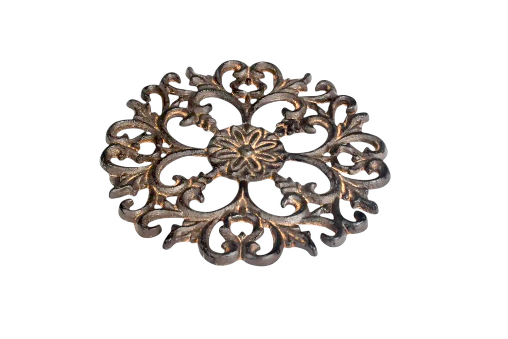 Acanthus design metal trivet pictured lying down on its base, against a white background.