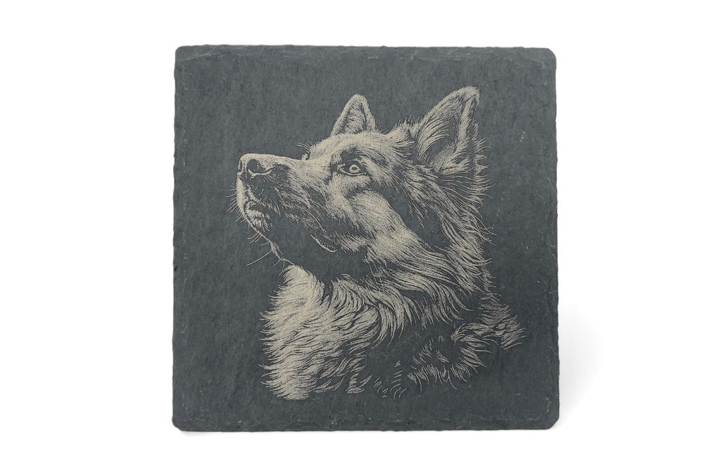 A slate coaster with the image of a alsation dog laser etched into the surface, on a white background.