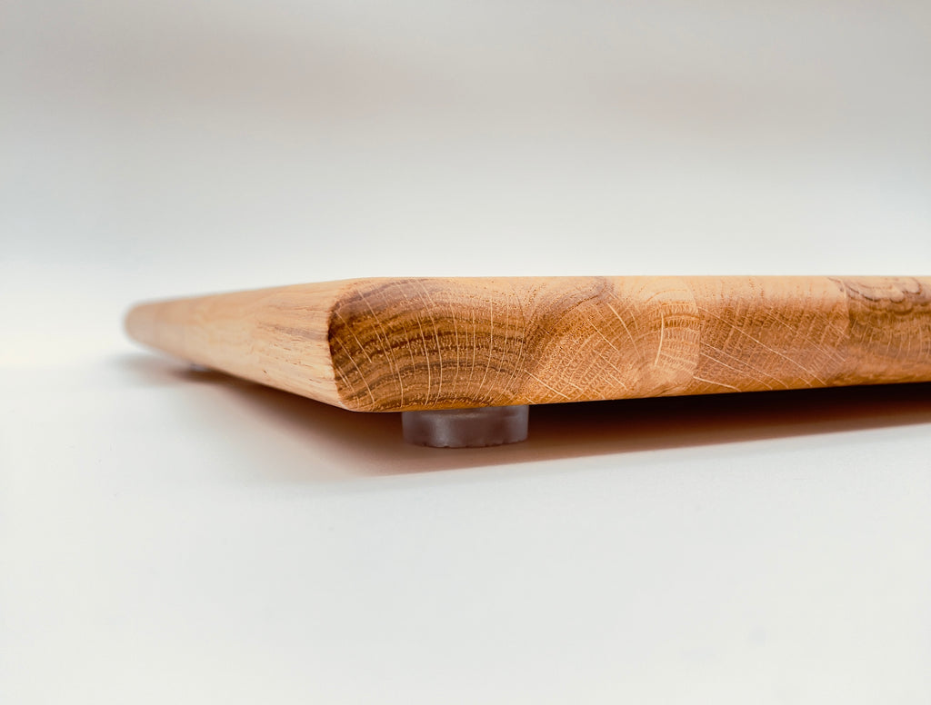 Table height close up shot of a large oak worktop saver, with a white background.
