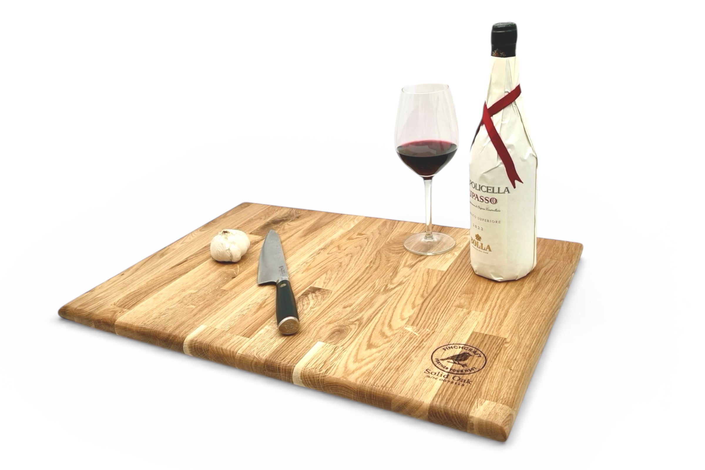 Wooden cutting board with knife, glass of red wine, and bottle on a white background