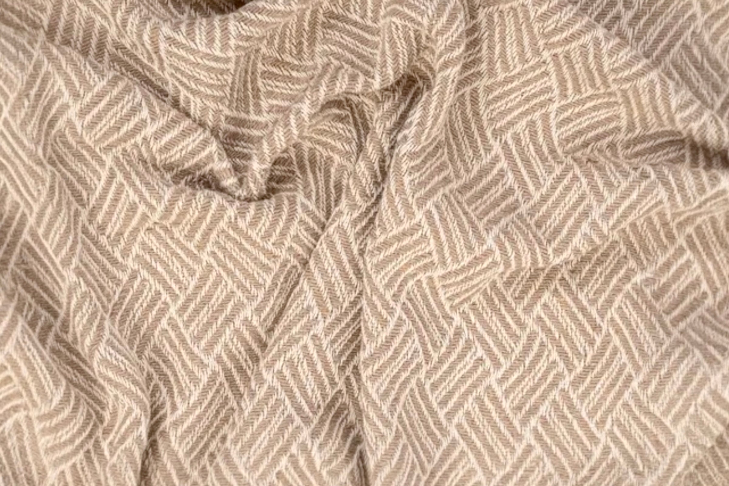 A close up of an oatmeal coloured handwoven cotton throw.