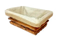 A rectangular breadbasket made from olive wood with a linen liner, against a white baclground.
