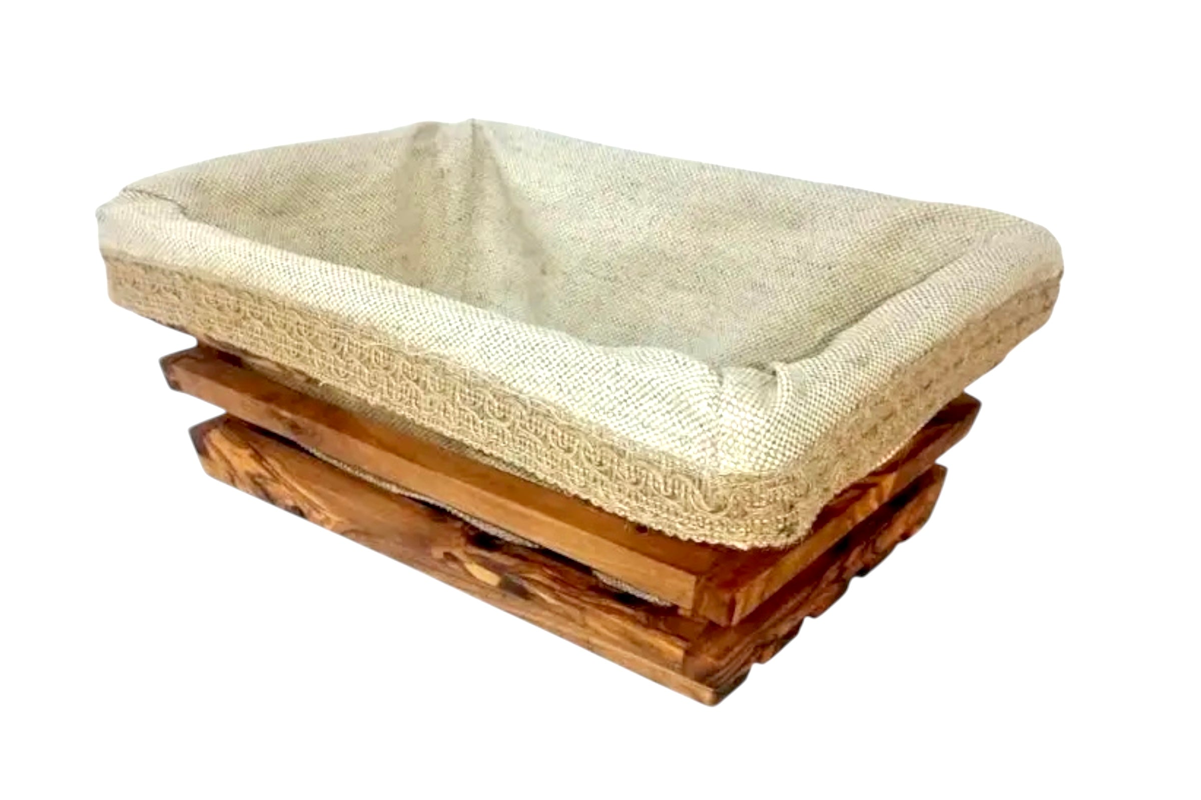 A rectangular breadbasket made from olive wood with a linen liner, against a white baclground.