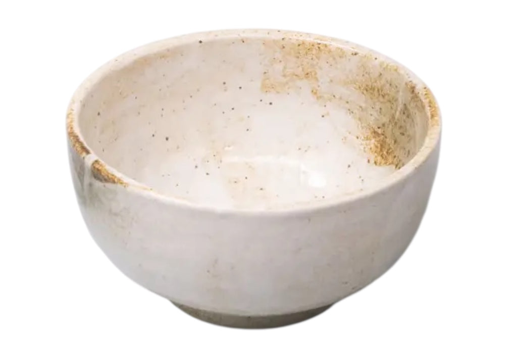 A small japanese porcelain rice bowl with a mottled cream glaze, set against a white bacground.