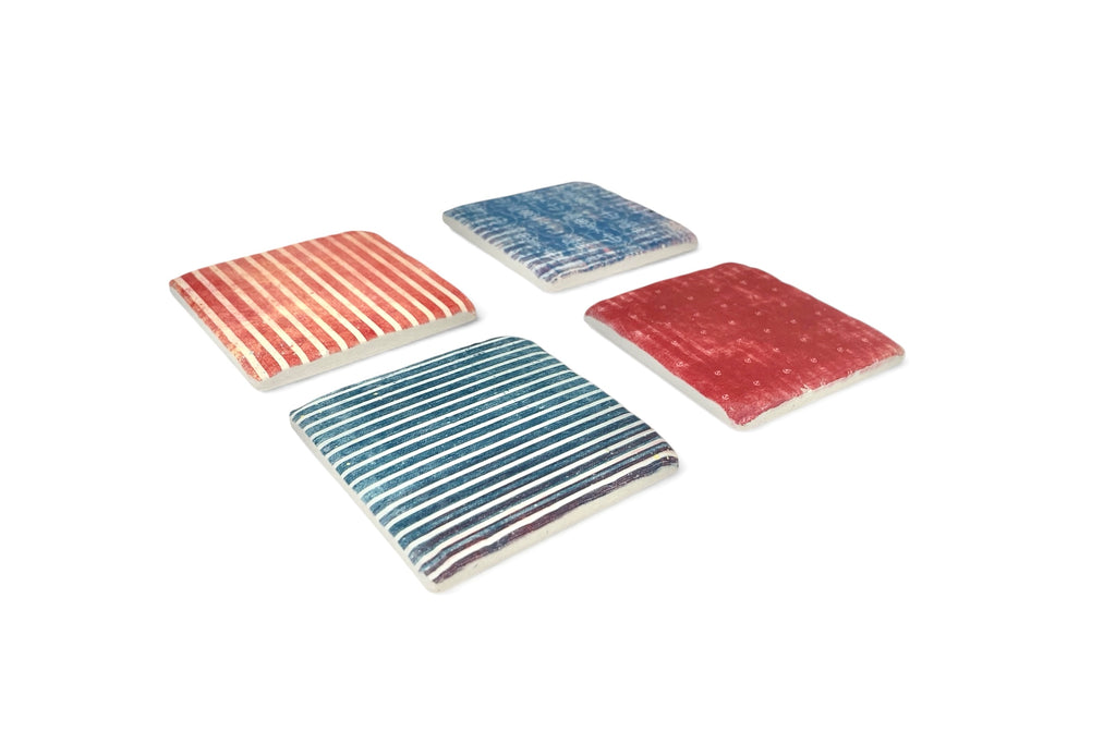 Four square coasters with striped patterns on a white background