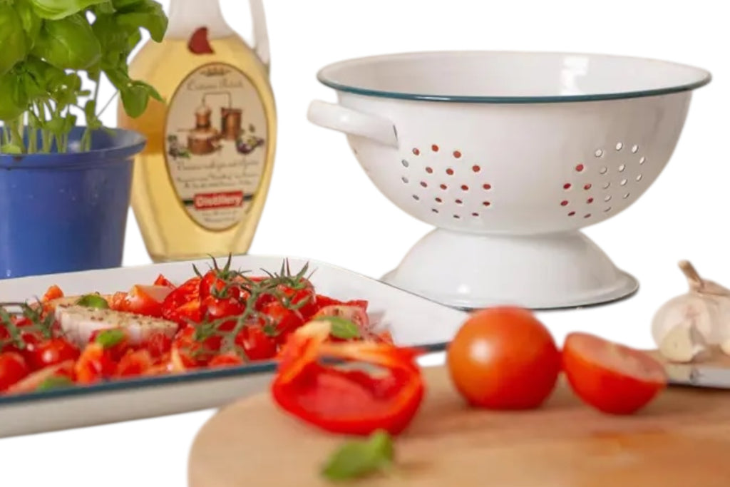 A 23.5cm enamelled steel colander finished in white with green accents. staged in a kitchen setting.