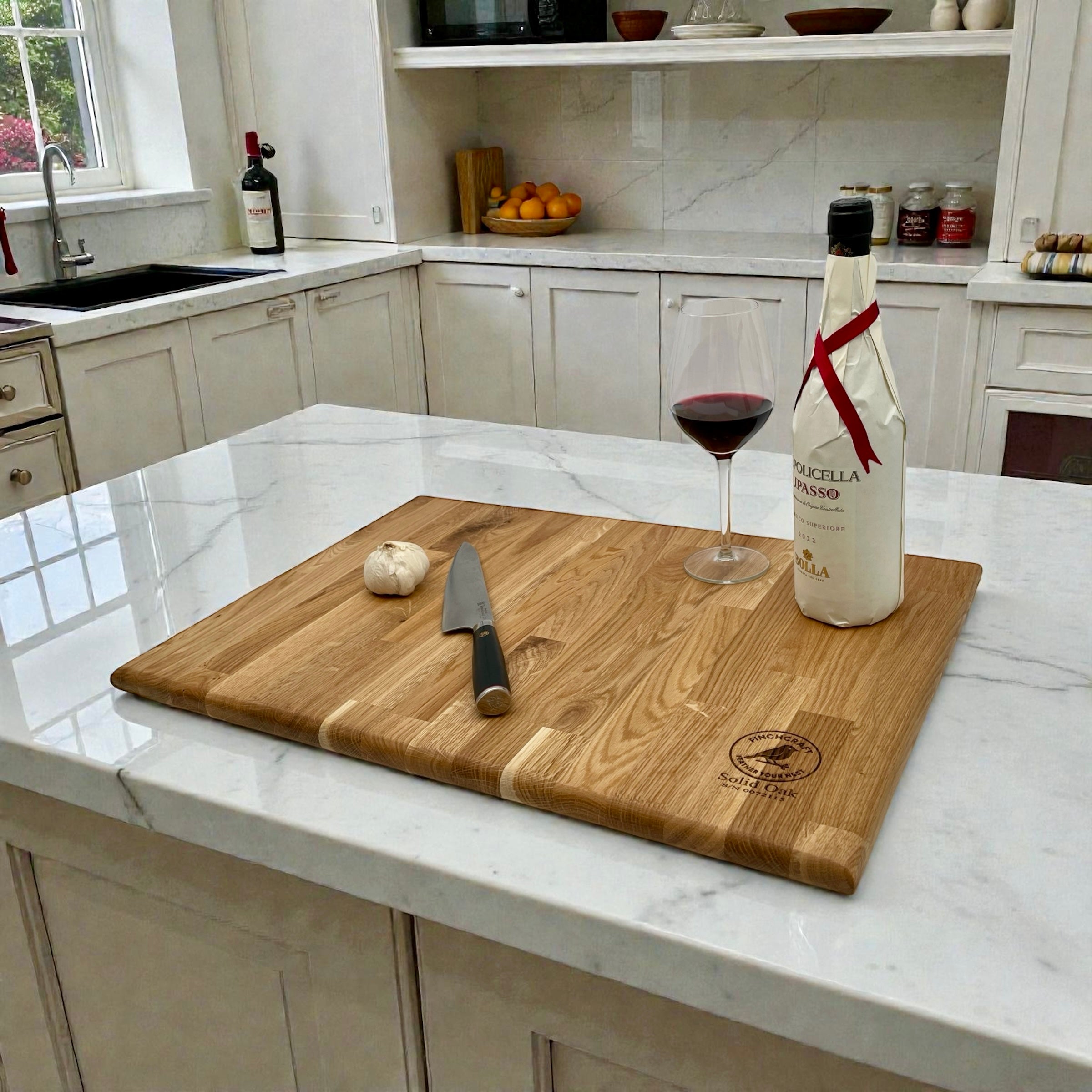 Large oak worktop saver with a knife, garlic, and a bottle of wine on a kitchen counter.