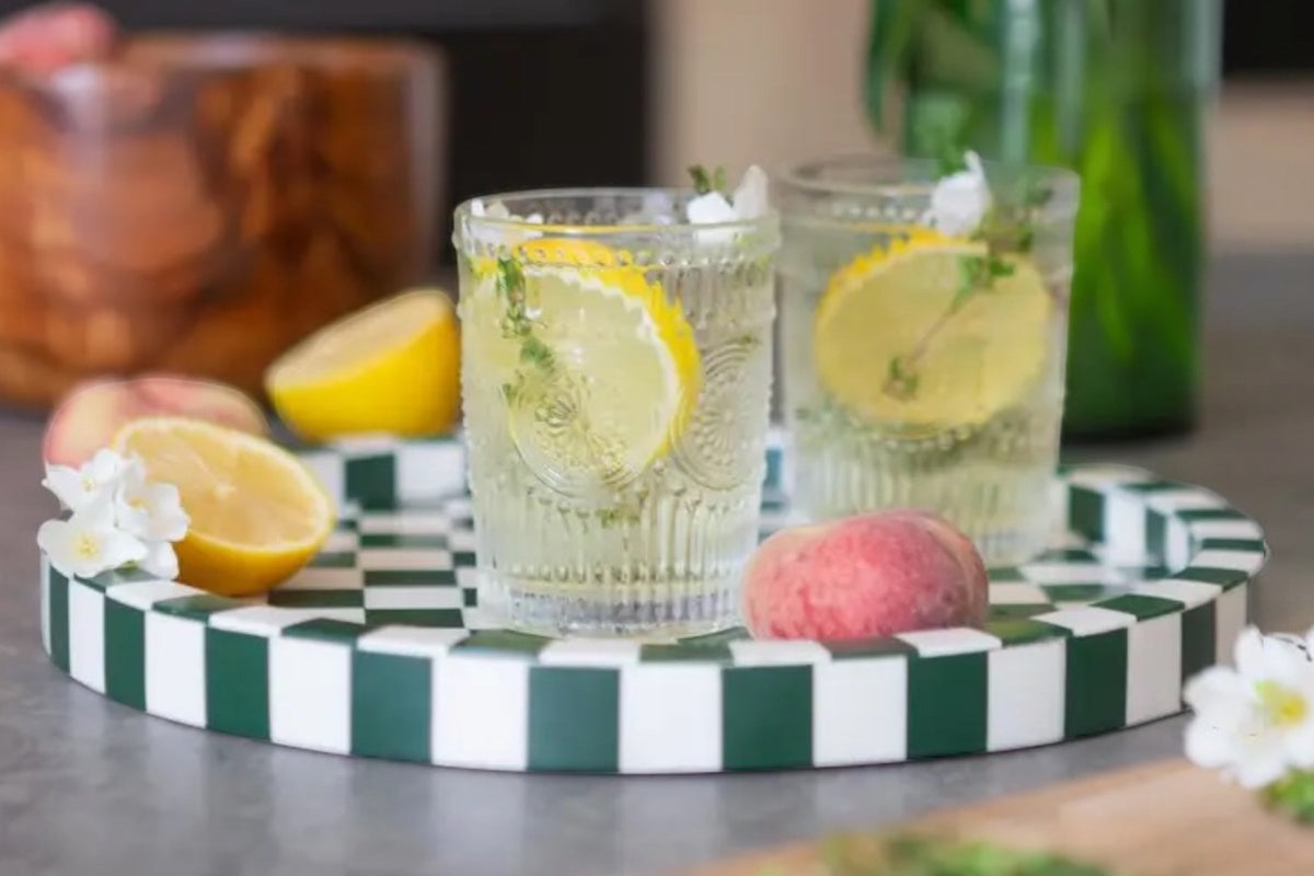 FINCHCRAFT set of clear glass tumblers with etched floral patterns, filled with lemon drinks on a checkered tray.