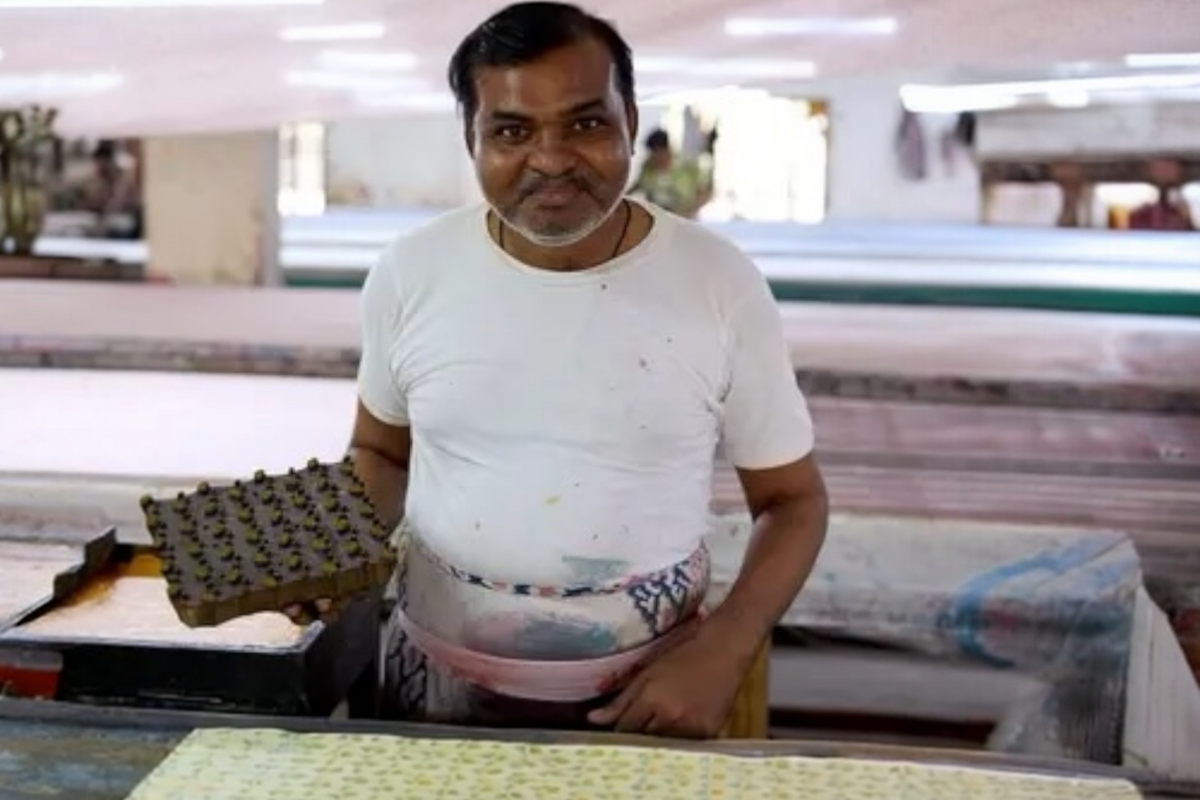FINCHCRAFT artisan hand block printing a sunshine yellow ditsy floral pattern onto cotton paper in a workshop