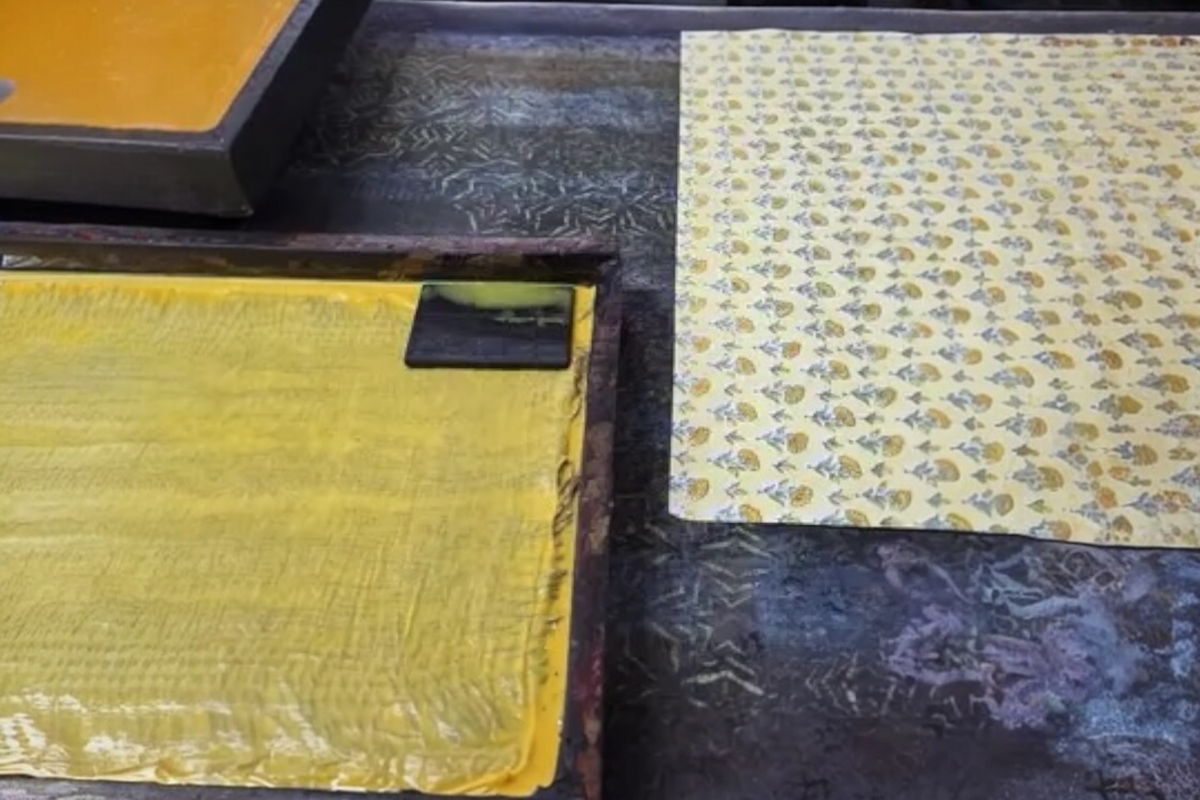FINCHCRAFT sunshine yellow ditsy floral block printed cotton paper sheet on a workshop table during the printing process.